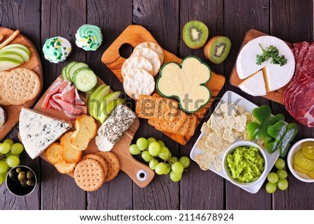 St Patricks Day theme charcuterie table scene against a wood background. Selection of cheese, meat, fruit and vegetable appetizers. Above view. Royalty-Free Stock Photo #2114678924