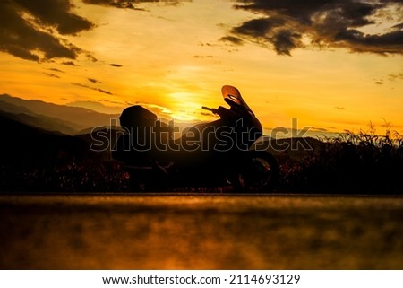 Silhouette of motorcycle parking in nature landscape background at sunset