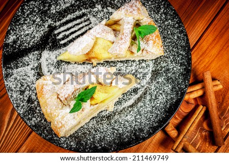 Traditional apple pie on black plate on wood table