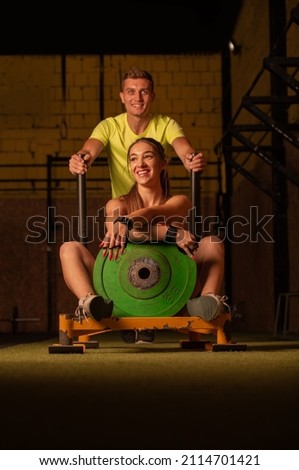 Handsome and fit guy is training while his girl is sitting and posing