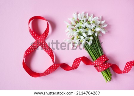 Background card for Women's day march 8, number eight from a red ribbon and a bouquet of flowers snowdrops. Royalty-Free Stock Photo #2114704289
