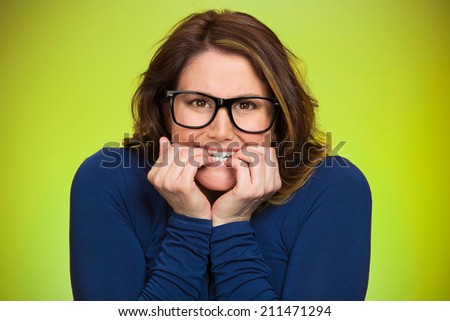 Closeup portrait nervous, stressed young woman, employee student biting fingernails looking anxiously, craving for something isolated green background. Human emotions, expression feeling body language