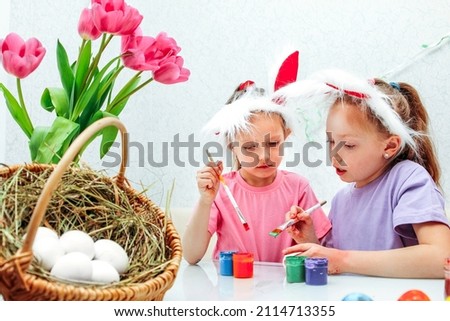 Two sister girls are enthusiastically coloring an Easter chicken egg Preparation for the bright Easter holiday. Friendship of two girls joint creativity Mutual understanding of two children free games