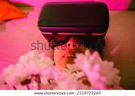 Woman wearing virtual reality glasses with flowers in her hands on virtual valentine's day