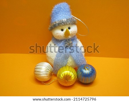Little snowman and balls. Snowman with a blue hat and scarf.