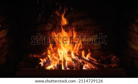 Burning firewood in fire-box of fireplace in country cottage. Keep warm. Fire in a fireplace with logs and flames creating a sense of warmth and coziness. 
