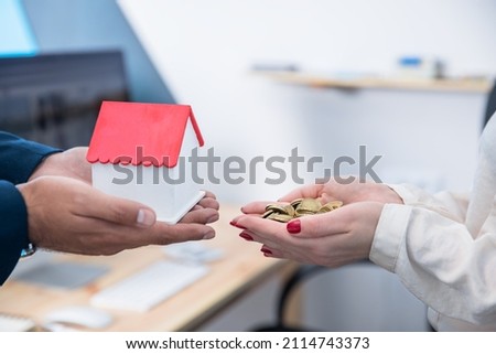 real estate, woman hand holding money with man hand house model

