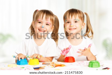 happy children twins girl draws paints , get dirty