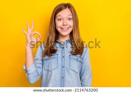 Photo of cool small blond girl show okey wear jeans outfit isolated on vibrant yellow color background