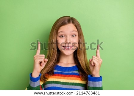 Portrait of attractive cheerful funny girly girl demonstrating up copy blank space isolated over vibrant green color background