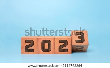 Happy new year 2023 . new year background concept,  flipping wooden cubes 2022 to 2023 with blue background.