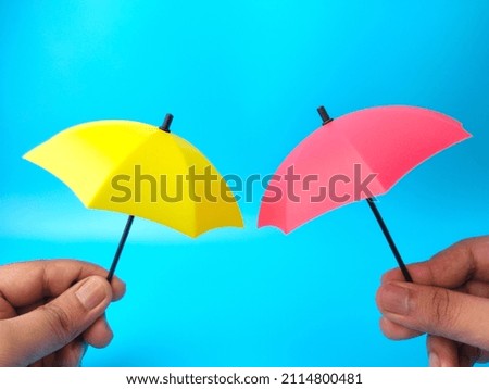 Hand holding two umbrella on blue background. 