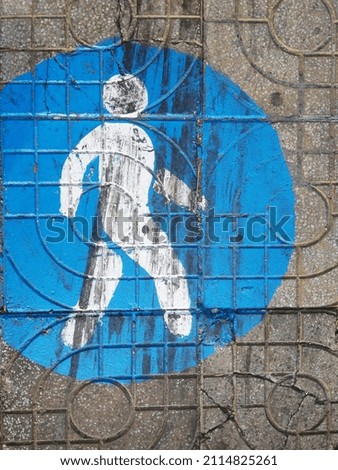 A walking man blue round traffic sign drawn on a sadewalk in Vietnam
