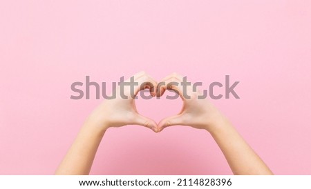 Banner young woman holding hands in shape of heart on pink background.