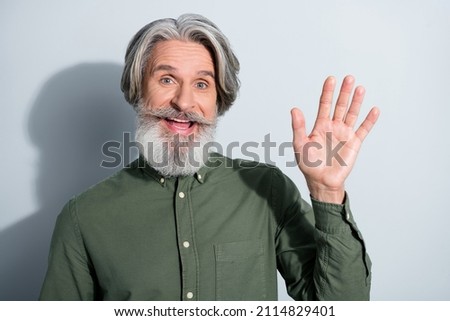 Portrait of handsome cheerful friendly grey-haired man waving palm hi hello isolated over gray pastel color background
