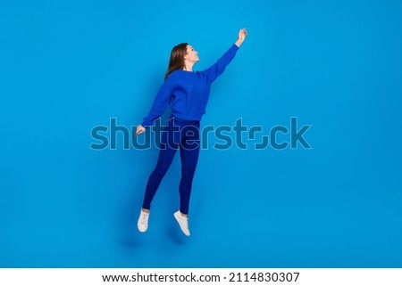 Full length body size view of attractive cheerful girl jumping holding copy space isolated on bright blue color background Royalty-Free Stock Photo #2114830307