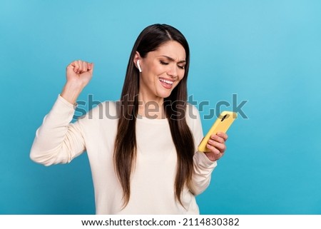 Photo of young excited lady use mobile earphones listen radio melody ear buds isolated over blue color background