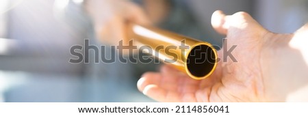 Hand Passing Golden Relay Baton To Businesswoman Royalty-Free Stock Photo #2114856041