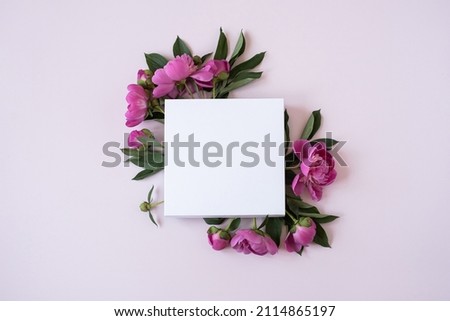 Wreath made of elegant pink peonies flowers with blank mockup copy space paper sheet on pastel pink background. Flat lay, top view brand, blog, website, social media template