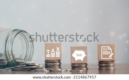 Wooden block with tax icons on stacked coins on white background. Tax Concept.
