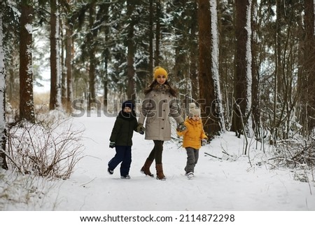 Happy family playing and laughing in winter outdoors in snow. City park winter day.