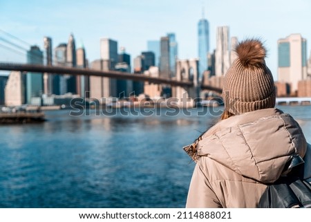 NEW YORK CITY WOMAN ENJOYING MANHATTAN VIEW FROM BROOKLYN PARK LIVING HAPPY DURING WINTER TIME IN UNITED STATES. TRAVEL, SUNNY DAY AND AMERICA CONCEPT.