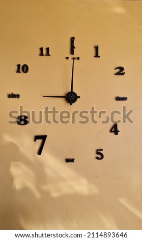 Golden brown cement wall decoration with wall clocks with numbers mixed with letters indicating the four main directions. 