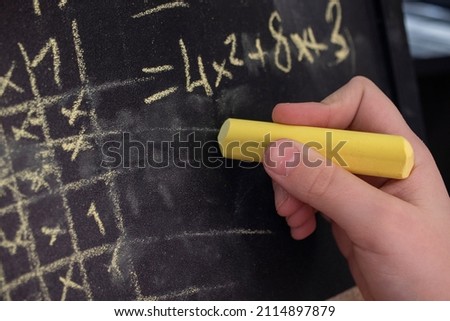 Girl doing math with chalk on blackboard. Royalty-Free Stock Photo #2114897879