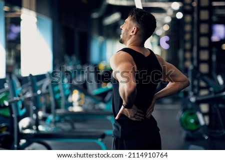 Portrait Of Young Arab Bodybuilder Suffering Lower Back Pain At Gym, Upset Middle Eastern Male Athlete Rubbing Painful Sore Zone After Getting Sport Injury, Having Lumbar Spine Ache, Copy Space Royalty-Free Stock Photo #2114910764