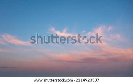 A beautiful sky painted by the sun leaving vibrant gold and pink hues. Clouds in the twilight sky, in the evening. Image of a cloudy sky in the evening. Evening sky scene with golden light  Royalty-Free Stock Photo #2114923307