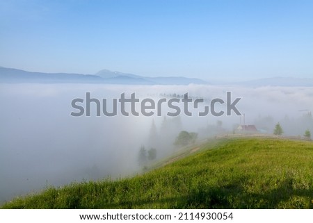 Mountains in deep fog, view from a meadow, Chornohora range with mountain Petros on the horizon.