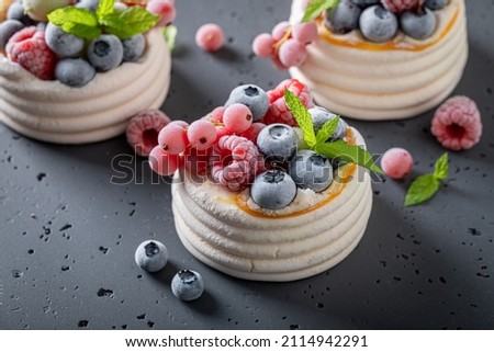 Homemade mini Pavlova dessert with whipped cream and frozen fruit. Dessert made of meringue with frozen berries and cream. Royalty-Free Stock Photo #2114942291