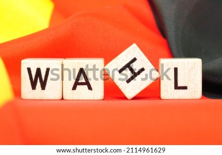 WAHL (choice), wooden cubes with letters on red background, closeup.