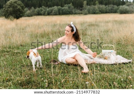 Caucasian beautiful girl on a summer day at a picnic. girl in a white dress and kerchief in a field. jack russell terrier dog playing with the owner. girl and dog playing. man and animal together. 