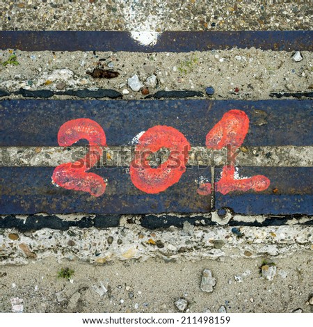 Number two hundred and one. Red lettering hand painted on metal strips in the ground.