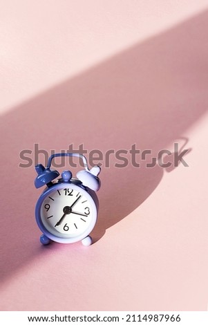 Violet vintage alarm clock on pastel pink background. Concept of time, morning, time to work or deadline.