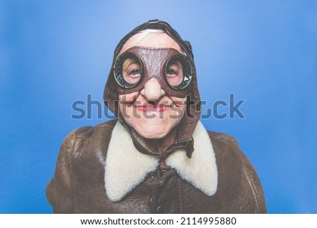 Funny portraits with old grandmother. Senior woman acting as an aviator from the first world war. Royalty-Free Stock Photo #2114995880