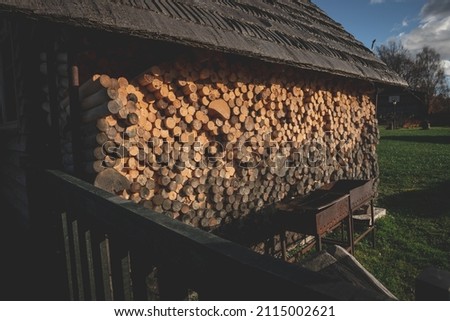 pile of chopped firewood under old barn roof