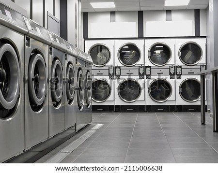 Row of industrial washing machines in a public laundromat Royalty-Free Stock Photo #2115006638