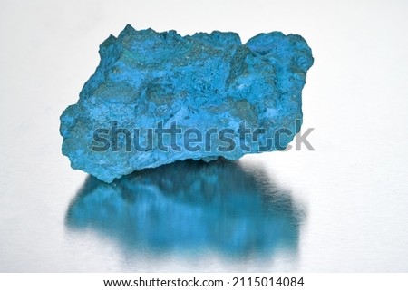 A single stone lies on a reflective background.