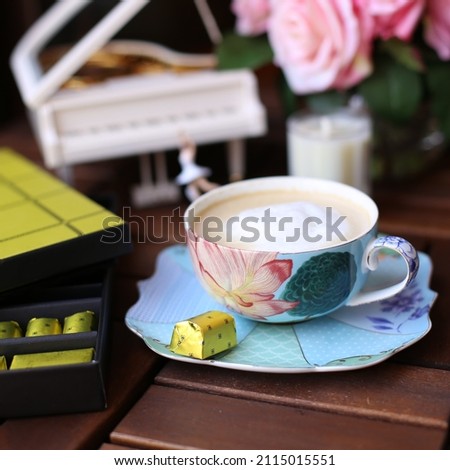 A cup of coffee with chocolate and pink roses and small piano 