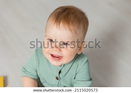 closeup portrait of a smiling baby in a green cotton bodysuit. products for children, early development, nursery kindergarten. space for text. High quality photo