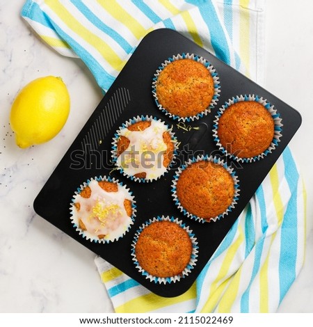 Freshly baked muffins with poppy seeds, lemon zest, icing sugar on a marble background. The concept of home baking. Citrus dessert. Breakfast for gourmets. Selective focus, top view, square picture