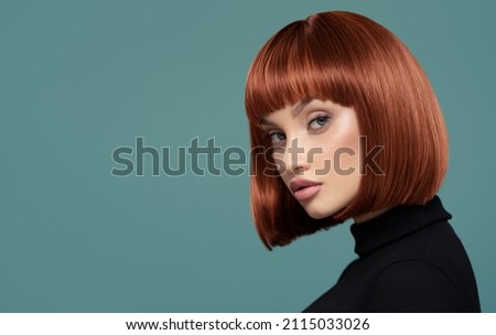Portrait of a beautiful girl with short red hair. Blue background.