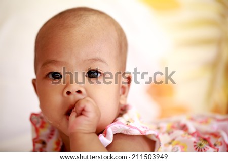 Asian baby girl lying and sucking her thumb