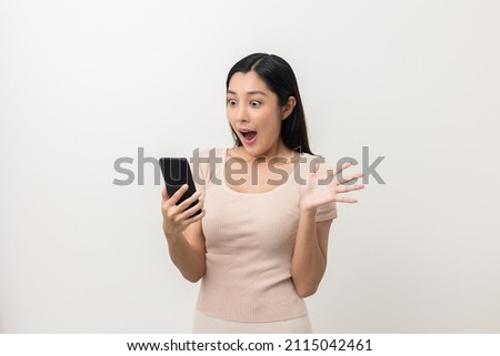 Surprised young Asian lady using mobile phone. Very Shocked face asia woman holding smartphone. Looking at cell phone screen. Victory moment. Very enjoy and fun relax time Royalty-Free Stock Photo #2115042461