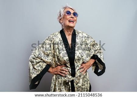 beautiful and elegant old influencer woman. Cool grandmother posing in studio wearing fashionable clothes. Happy senior lady celebrating and making party. Concept about seniority and lifestyle Royalty-Free Stock Photo #2115048536