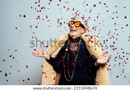 image of a beautiful and elegant old influencer woman. Cool grandmother posing in studio wearing fashionable clothes. Confetti explosion on her 90s birthday celebration