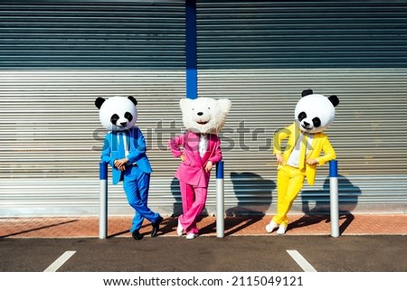 Storytelling image of a couple wearing giant panda head and colored suits. Man and woman making party in a parking lot. Royalty-Free Stock Photo #2115049121