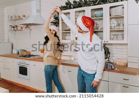 Happy beautiful couple of lovers celebrating Christmas at home - Winter holiday season, celebration of xmas eve in a decorated apartment